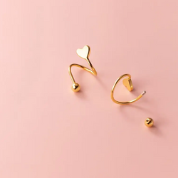 Single Twisted Heart Ørering: En elegant ørering med piercing lås, der forestiller et lille hjerte tæt på øreflippen, bagved er hjertet twister og tilføjer en subtil drejning til det klassiske symbol, lavet af høj kvalitet 925 sterlingsølv og forgyldt med 18 karat guld.